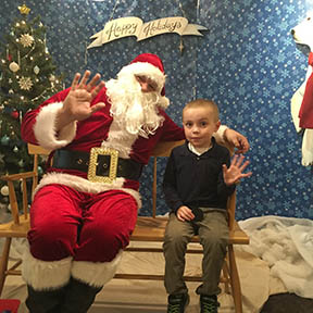 Young boy sitting with Santa and waving