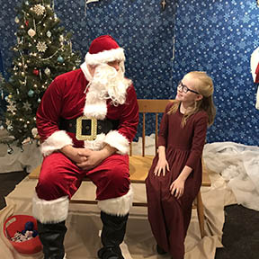 Young girl sitting with Santa, smiling