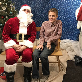Santa sitting with young teen boy smiling