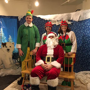 Santa sitting with three elves
