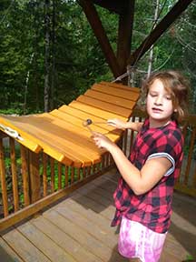 Young girl playing outdoor wooden xylophone