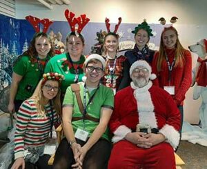 Group of college students dressed as elves with Santa