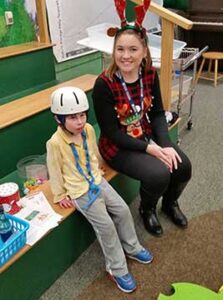 Young boy with helmet sitting with Santa elf student