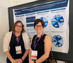 Drs. Howorth and Rooks-Ellis smiling in front of their conference poster