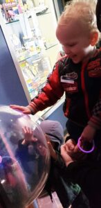 Two young boys touching clear globe, smiling, at Astronomy Center