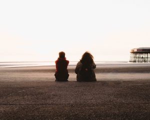 two people sitting on a beach