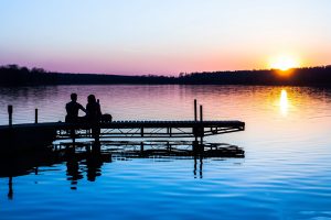 two people sitting beside a lake