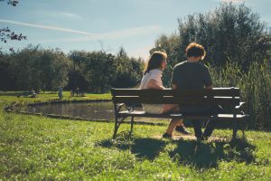 two people sitting on a park bench