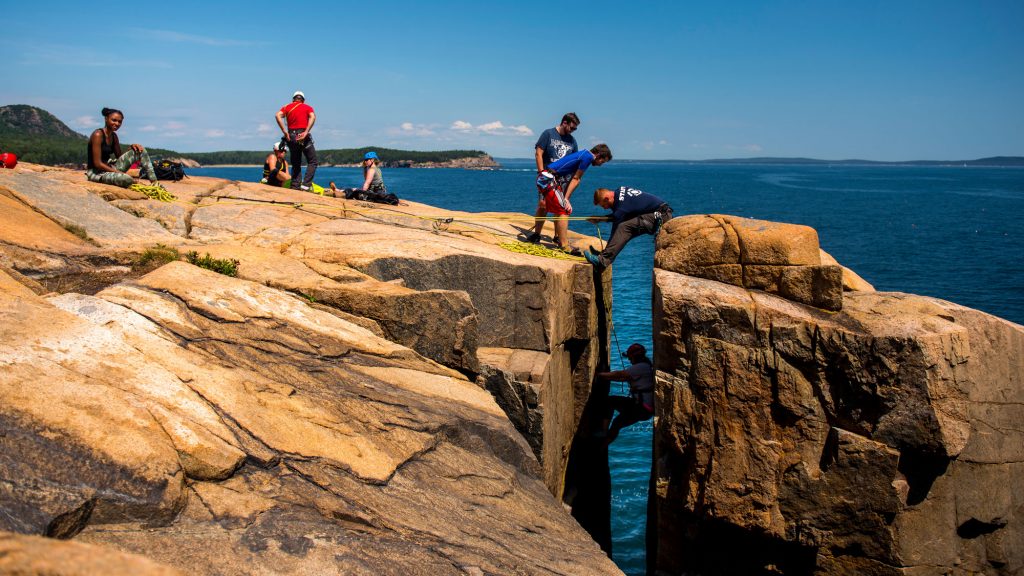 a group climbing over the ocean
