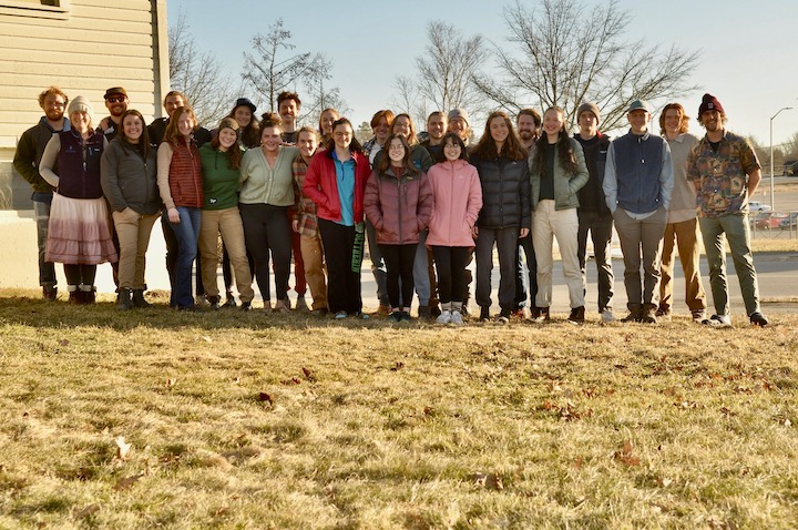 A group gathers together for a picture under a blue sky