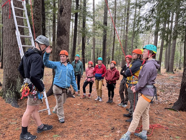a group in a semi-circle wearing helmets and harnesses