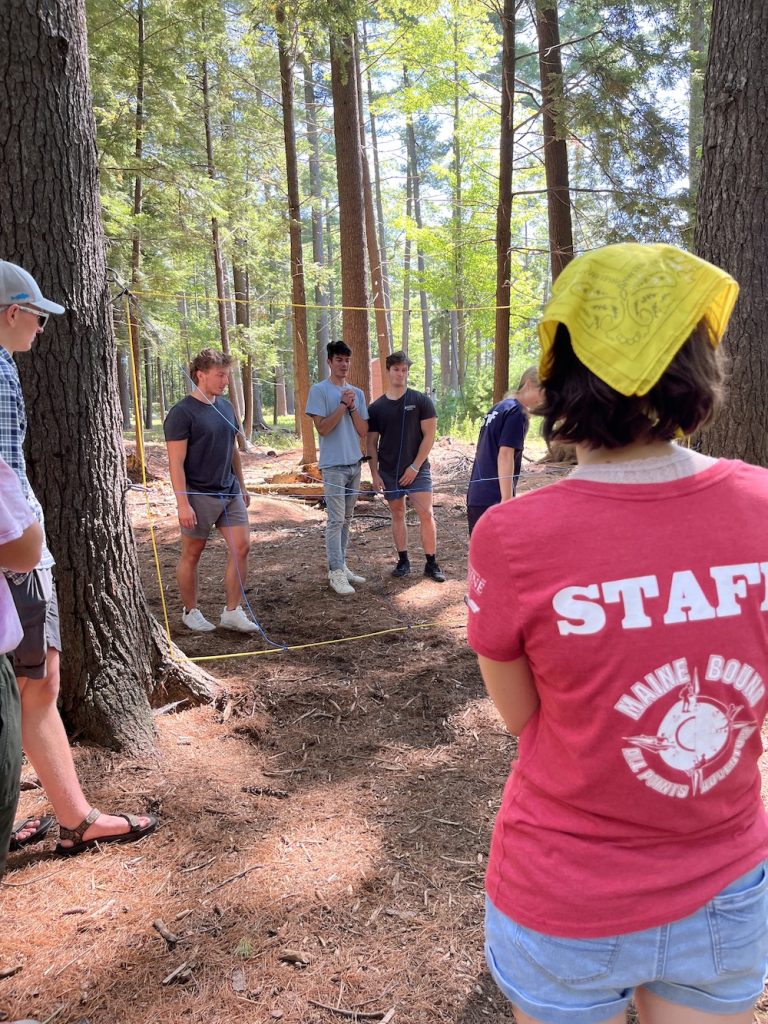 Back of individual wearing a red staff shirt watching a group