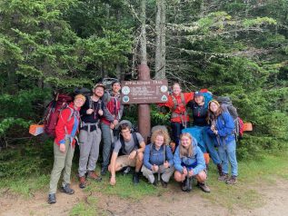 A group poses around an Appalachian trail sign