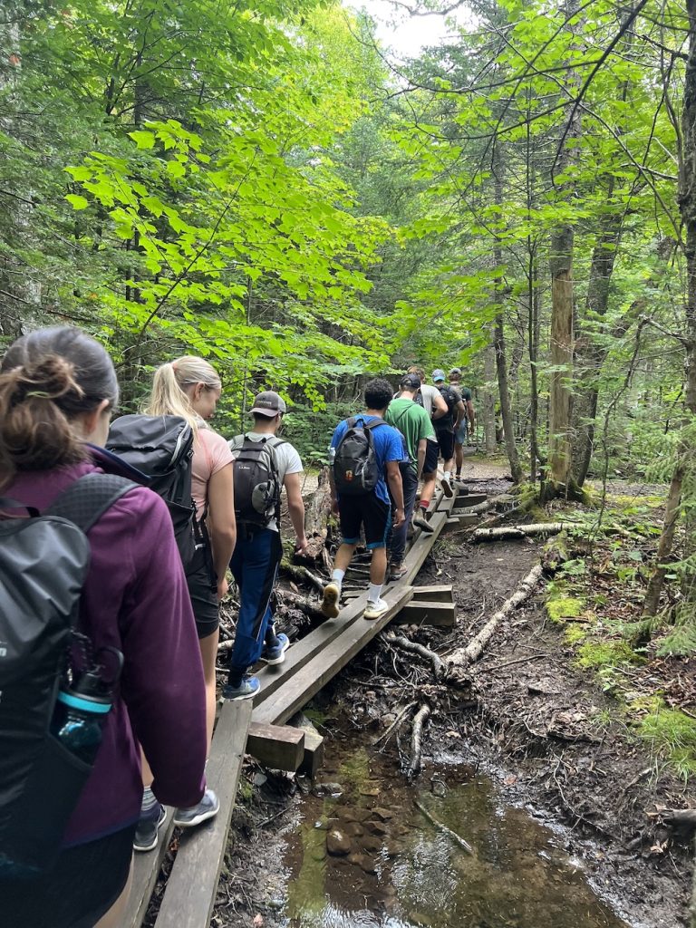 A group walking across wooden bridges through the woods