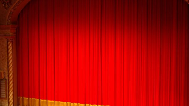 image of a brightly lit stage with red curtains