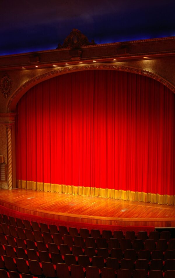 image of a brightly lit stage with red curtains