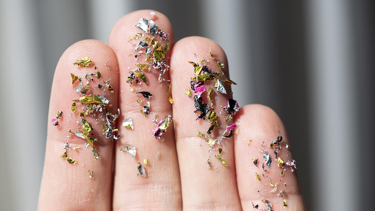 A photo of fingers with microplastics stuck to them