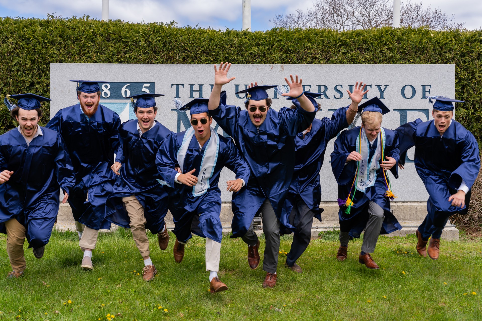 A photo of students in graduation caps and gowns running toward the camera