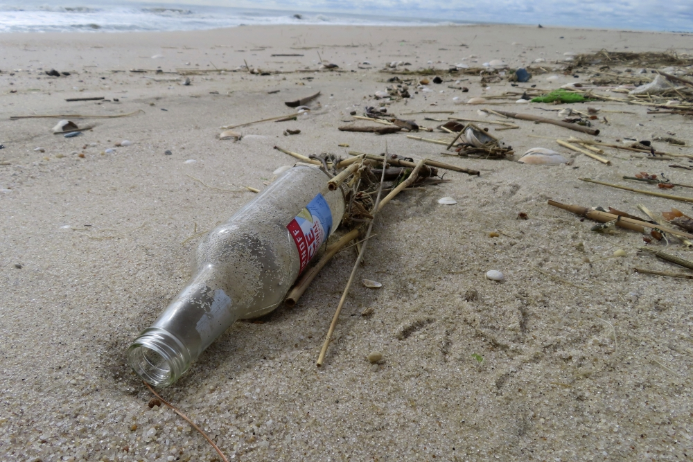 a discarded bottle in the beach sand.