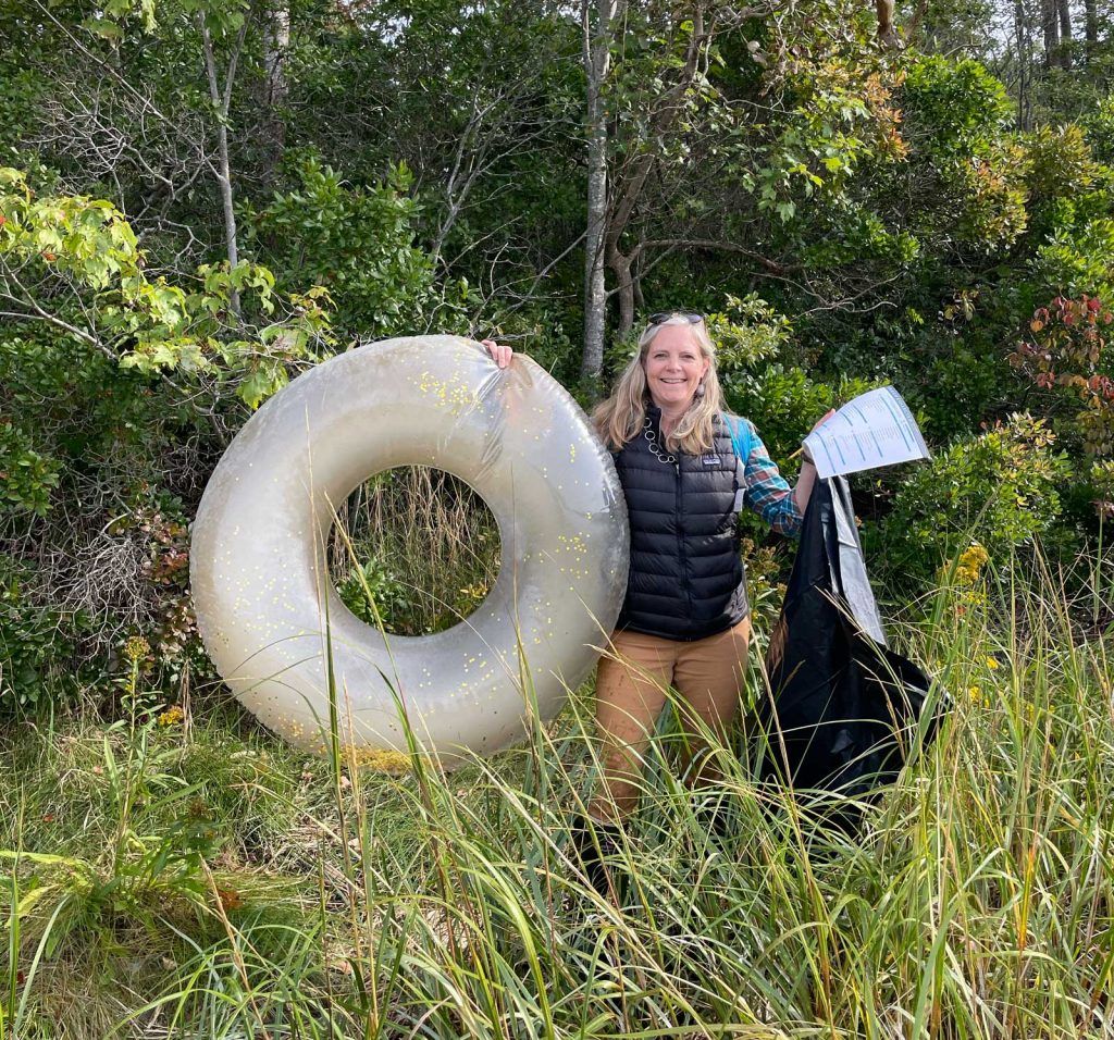 Woman holding up raft and other marine debris.