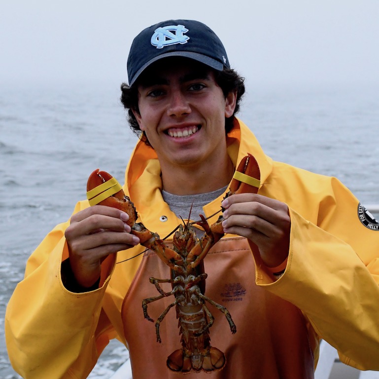 Kyle Oliviera in a yellow rain jacket holding a lobster