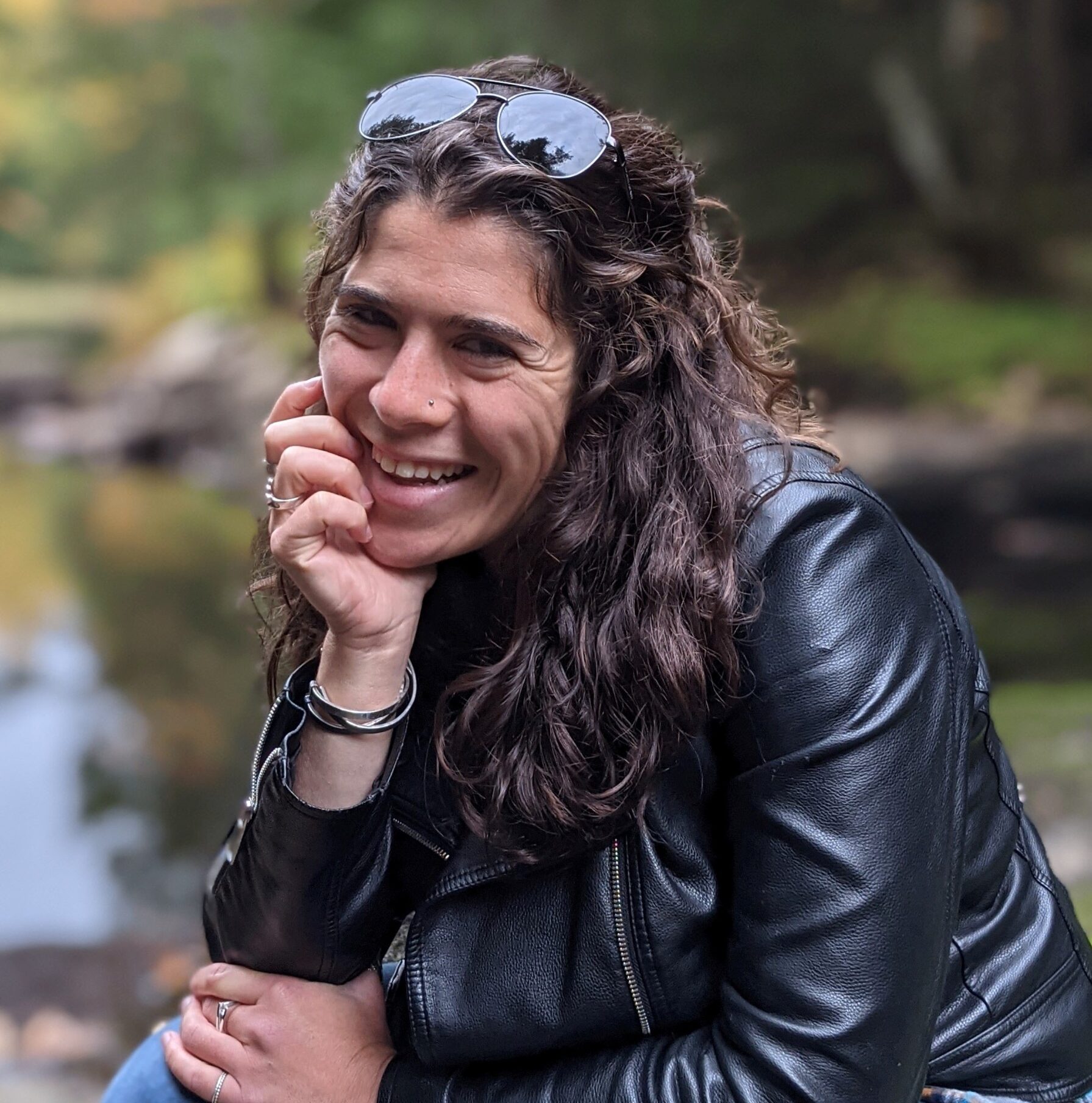 Rene Francolini in leather jacket smiling by water