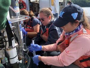 Graduate students collect water from a sampling device.