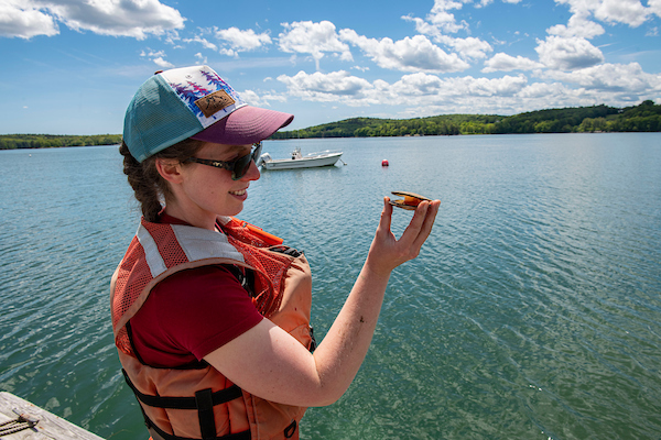 Student at the Darling Marine Center by the water holding a clam