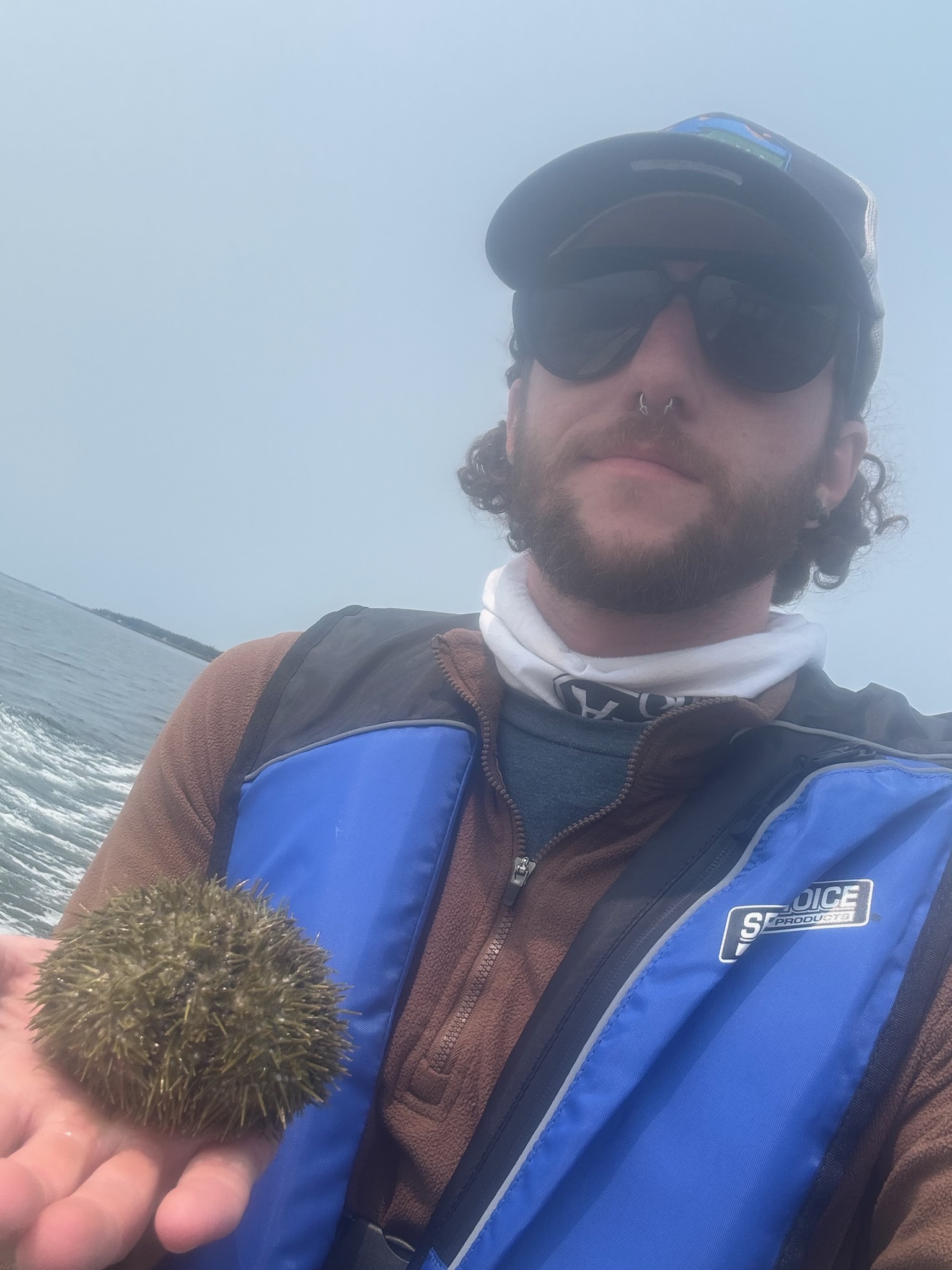 Chandler Sendek on a boat in fog holding a sea urchin