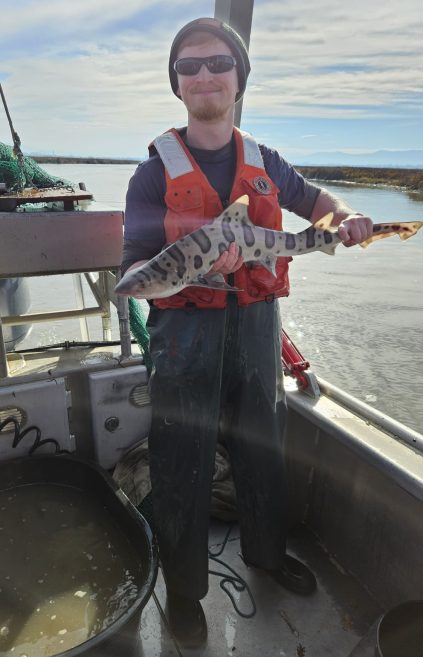 Brian Alper on a boat holding a small shark