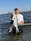 Spencer Kubo waist deep in water holding a fish
