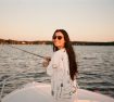 Jessica fishing on bow of boat with sunglasses
