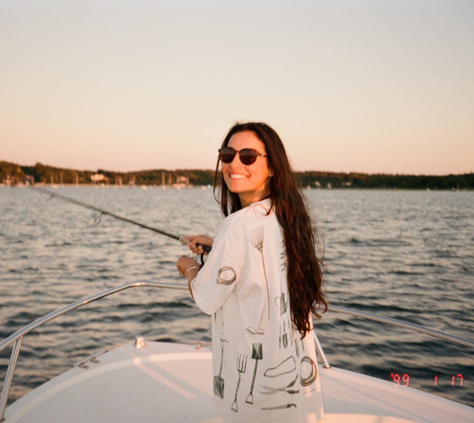 Jessica fishing on bow of boat with sunglasses