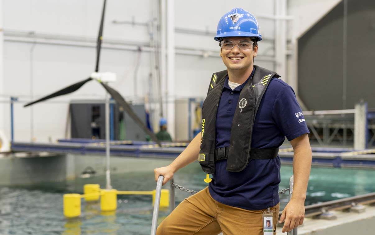 A photo of a student in front of a wind turbine