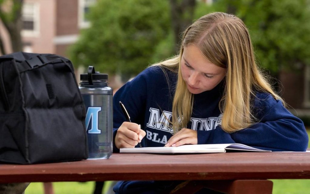 A photo of a person writing at a picnic table