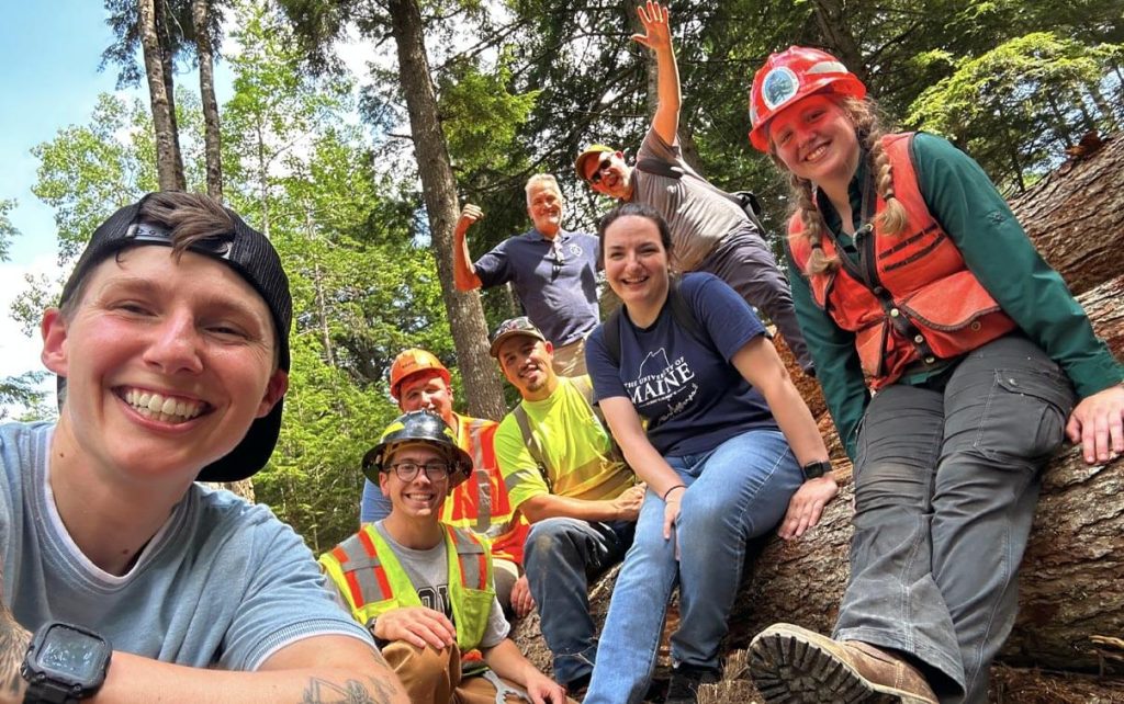 A photo of a group of people in the forest smiling at the camera