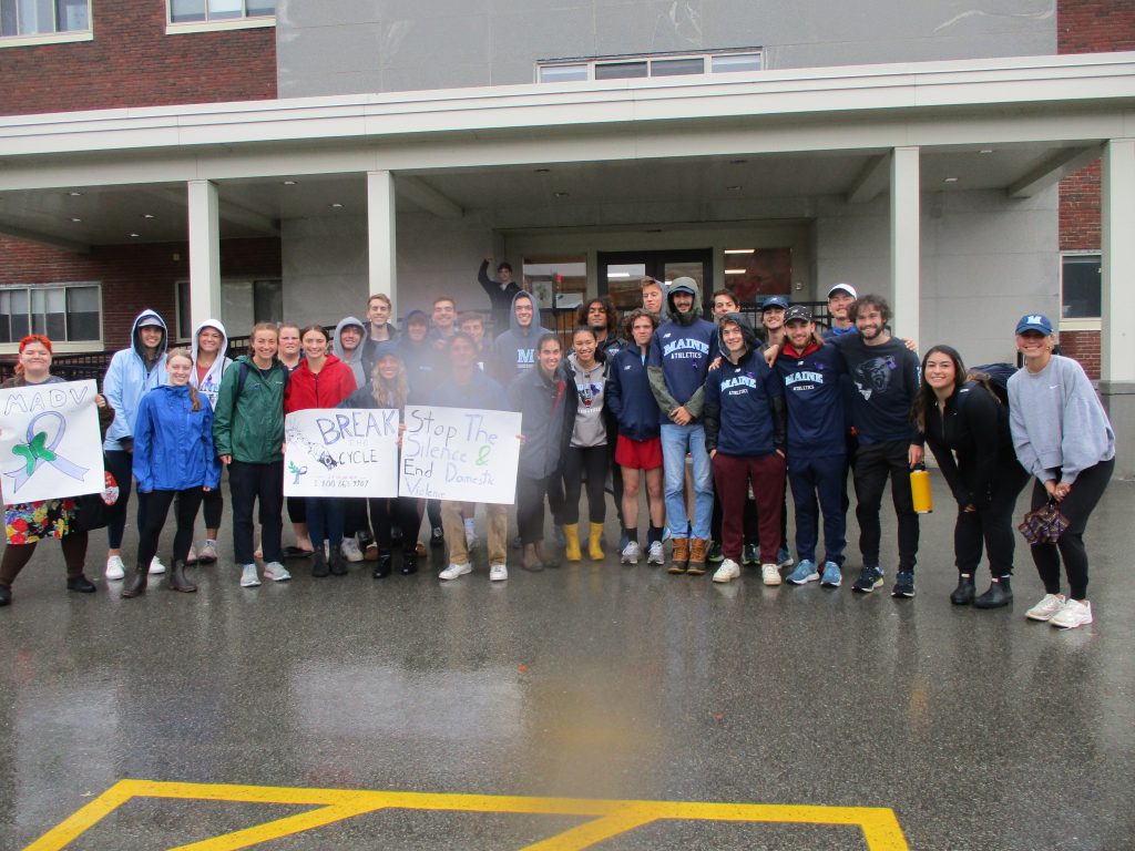 Students gather in front of Gannett Hall with signs