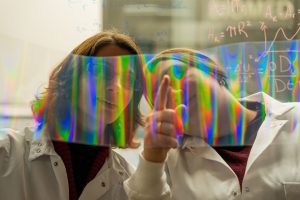 Engineering students looking at a paper that projects rainbow colors