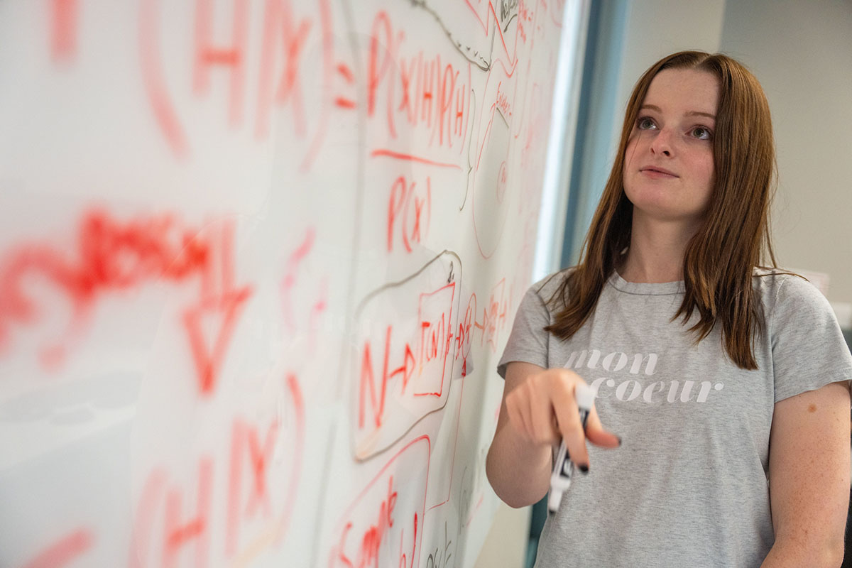 A photo of a girl writing out some code