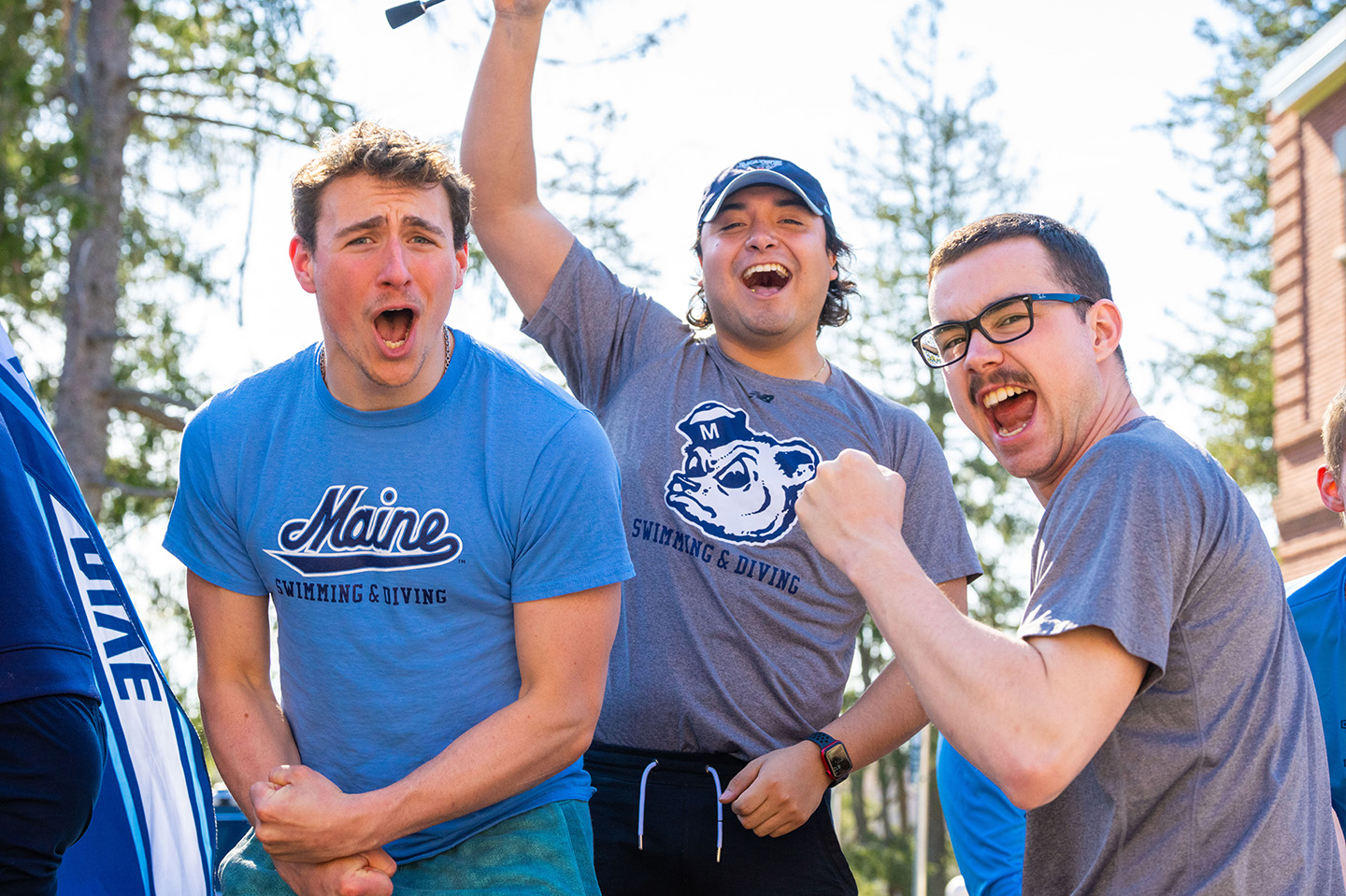 UMaine students cheering wearing UMaine branded clothes