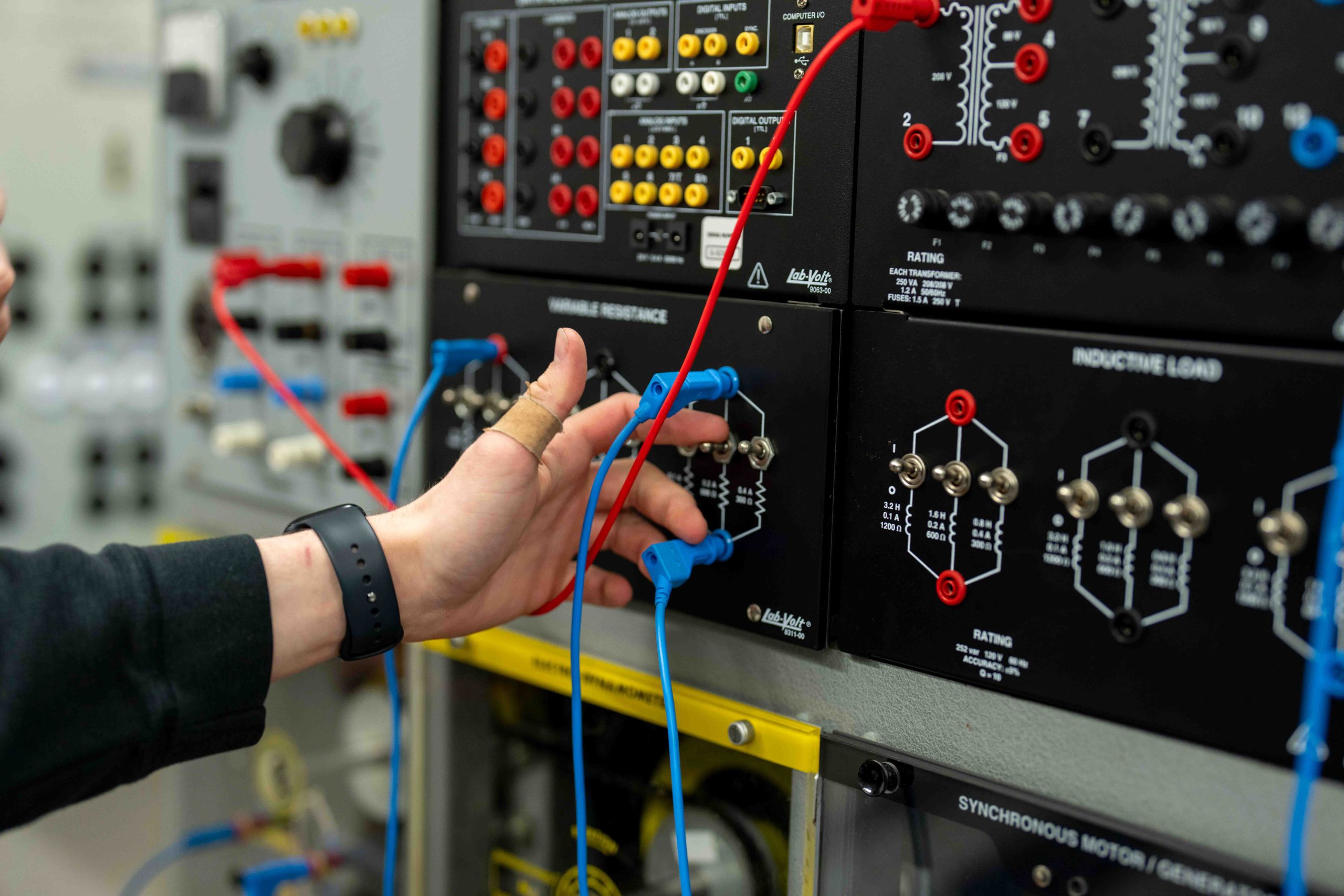 Electrical Engineering lab student reaching out at a power grid with cords