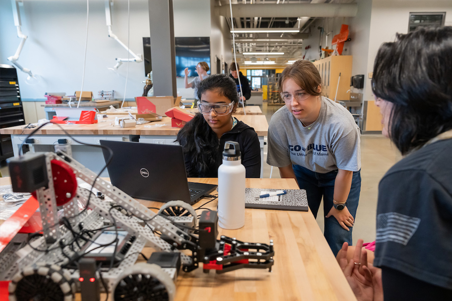 Engineering students working on a computer with robotics on the table