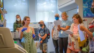 Sydney Greenlee stands in lab surrounded by others as she leads workshop.