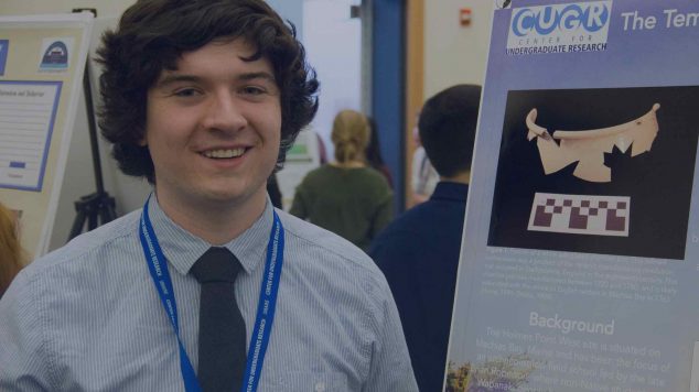 student in front of research poster at conference