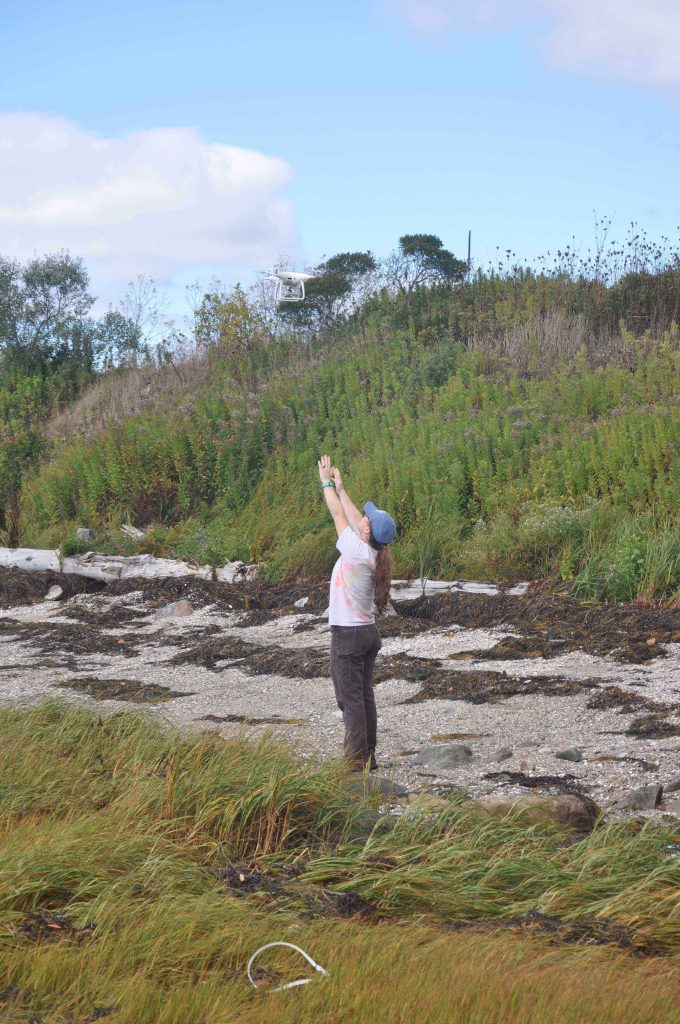 A woman launching a drone on a beach