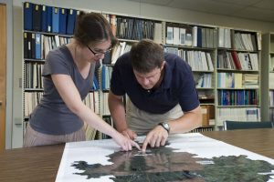 SSI graduate students Michelle Johnson and Spencer Meyer discuss conservation areas on a map of the Penobscot River watershed.