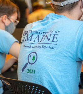 Back of student wearing blue tee shirt that says University of Maine, Research Learning Experience 2021