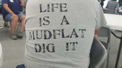 View of the back of a tee shirt with the words "Life is a mudflat dig it"
