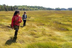 Suzanne Greenlaw and Shantel Neptune walking through a salt marsh