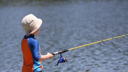 Young boy fishing from lake shore
